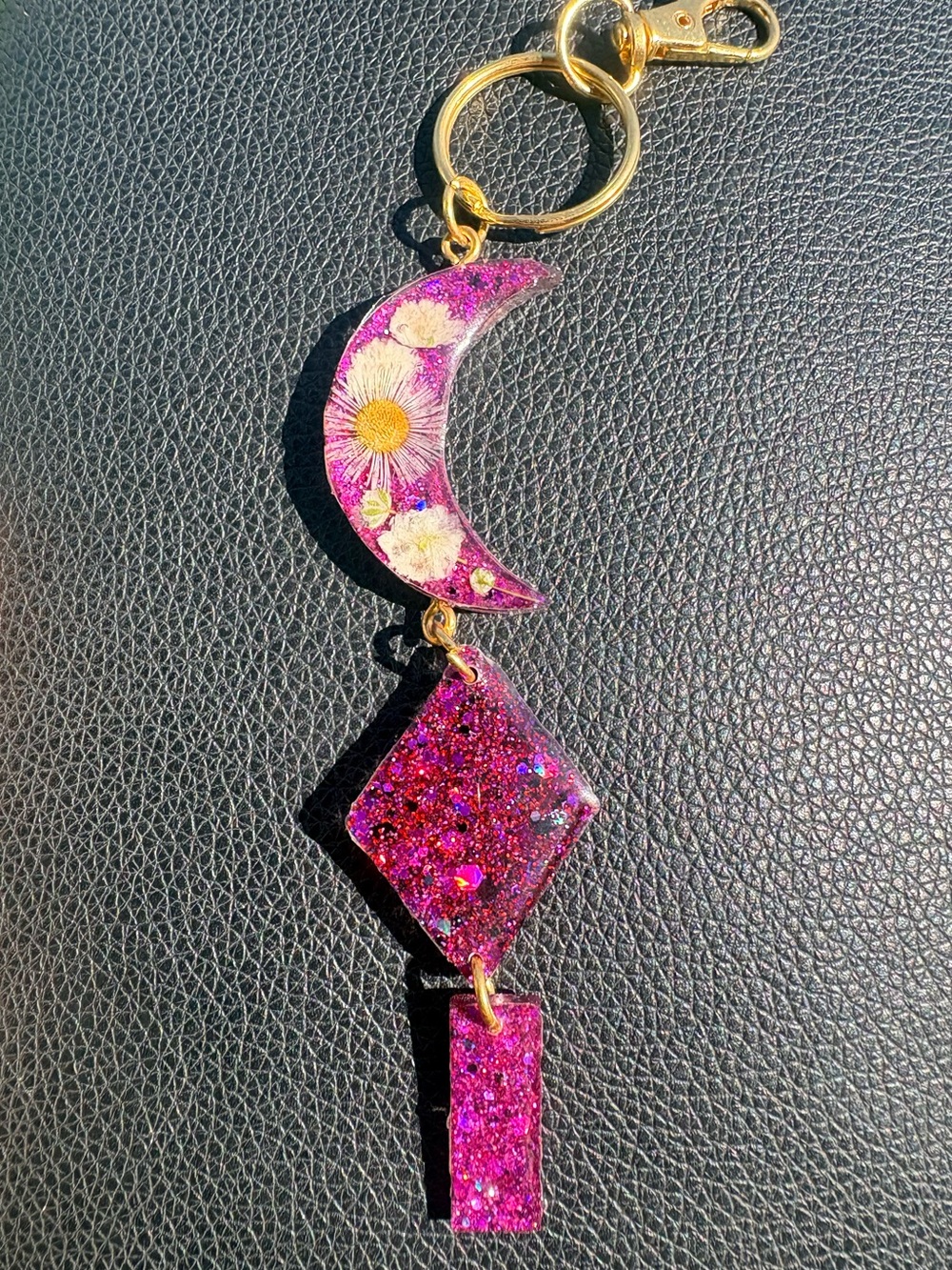 Pink glittered magenta pressed flower moon keychain charm with gold hardware